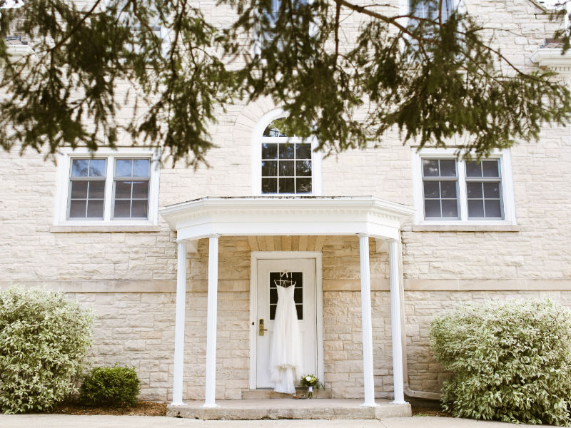 wedding dress hanging on the patio of a historic, brick building